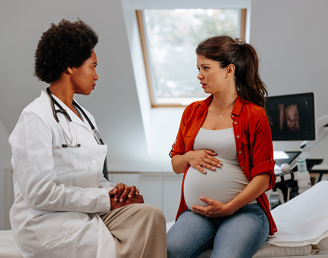 Pregnant woman consulting with female doctor