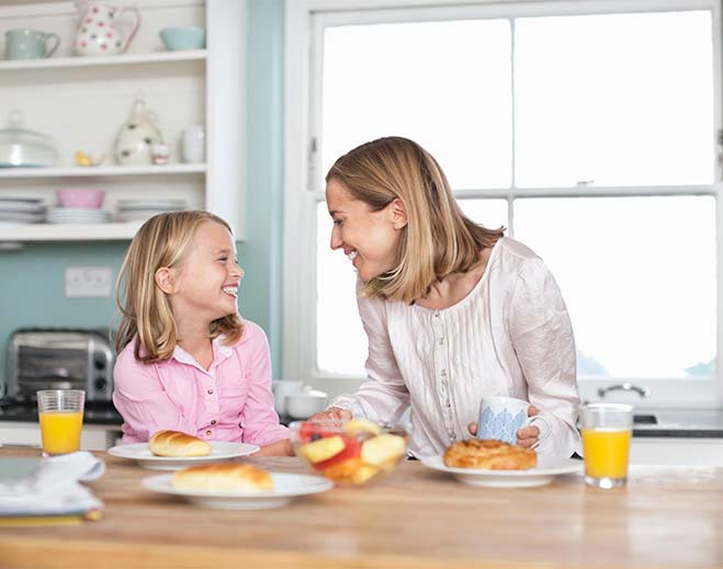 happy mom and daughter eating breakfast